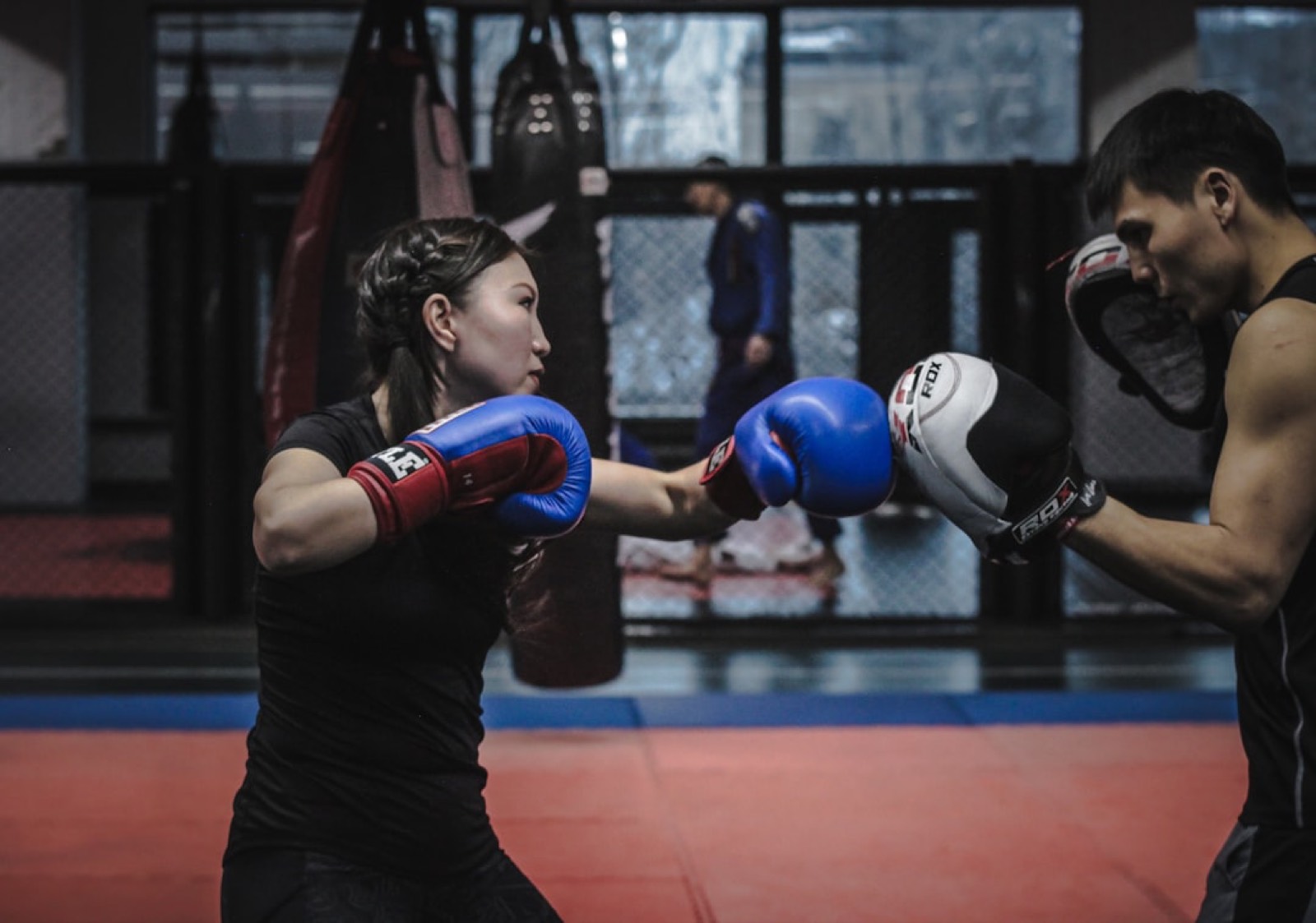 Une femme essaie un cours de boxe en salle, gants aux poings, lors d'une première séance